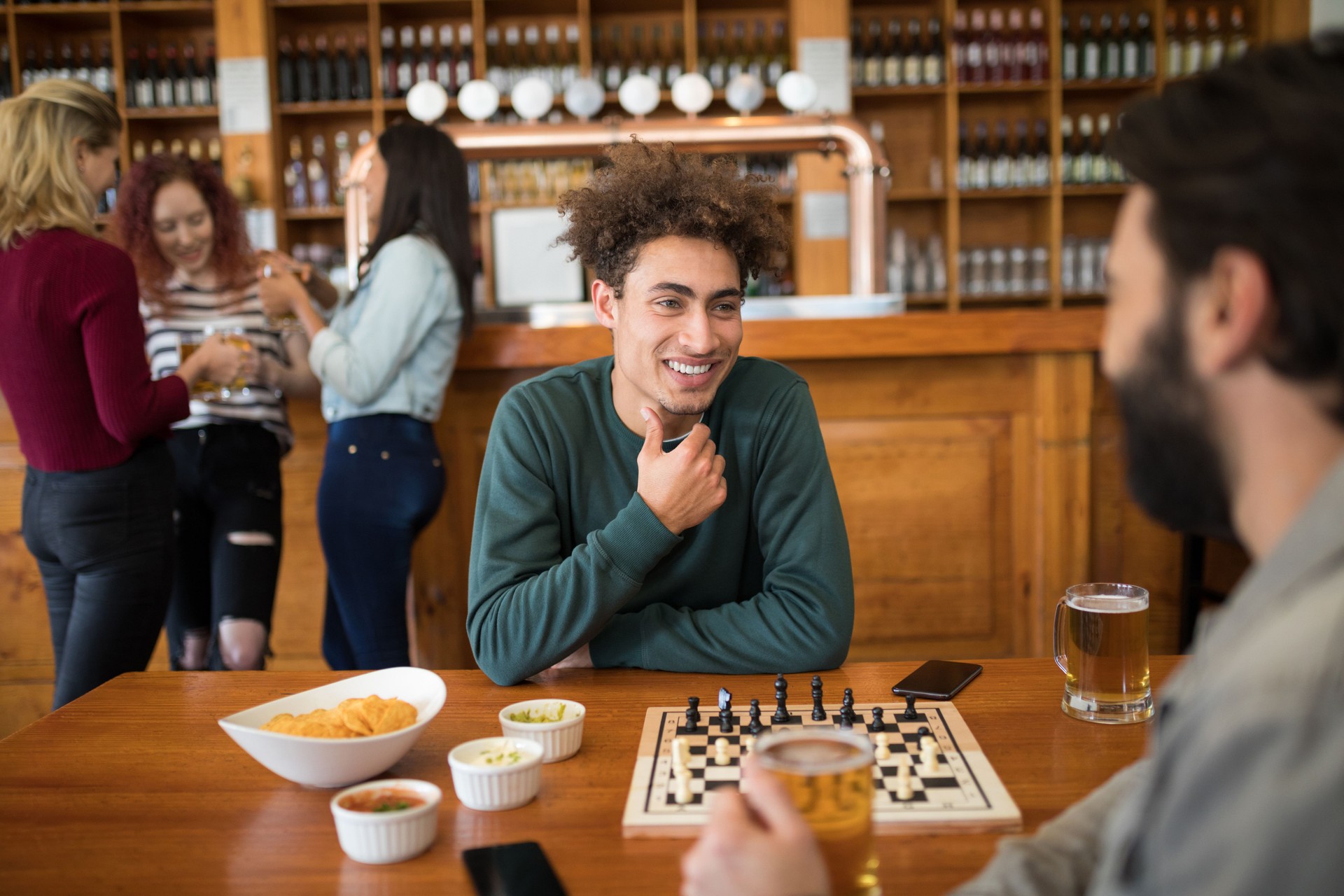 Two adult men playing chess while having glass of beer Two adult men playing chess while having glass of beer